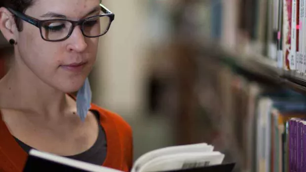 Photo: Woman with MS reading book in library 