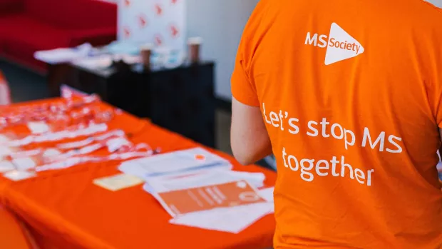  A table of MS Society publications and a person in a t-shirt that reads 'Let's stop MS together'