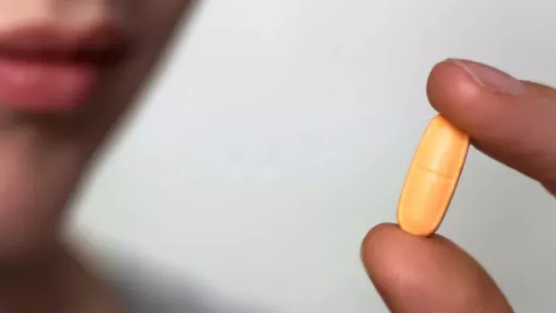 A person holding an orange pill 